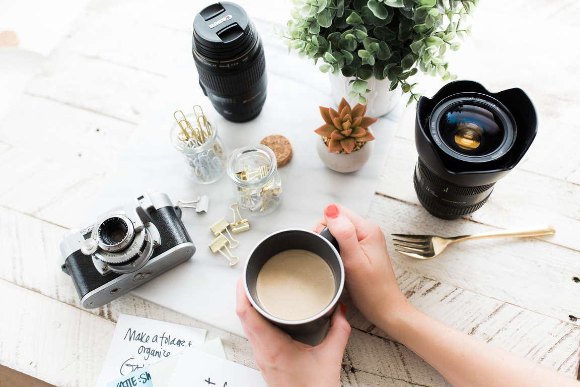 Hand Holding Coffee with Photography Equipment